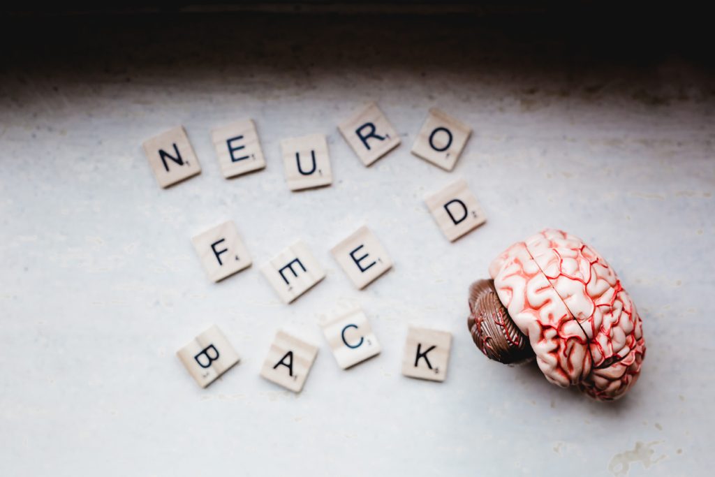 Scrabble-Steine zeigen "Neurofeedback", daneben ein Gehirn-Modell
